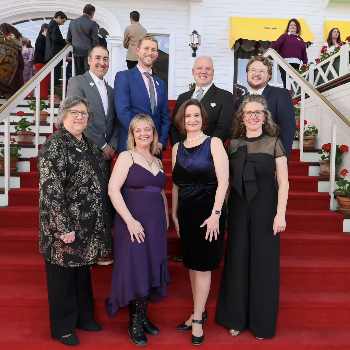 Eight members of the MSCI Board of Directors in evening dress, in two rows on the red-carpeted steps of the Grand Hotel